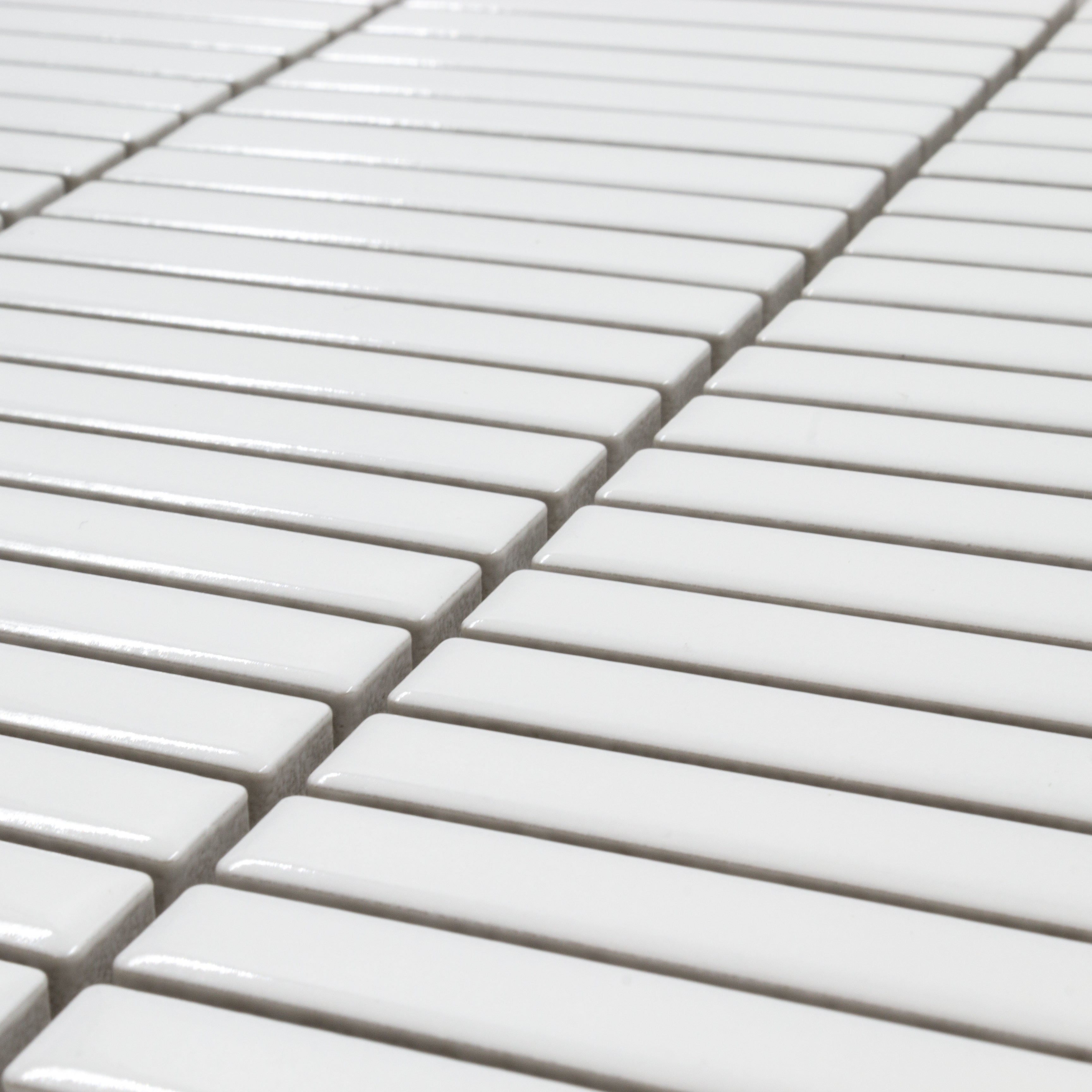 Angled close up view of a single sheet of mini kitkat stacked mosaic tiles in white glossy. The sizing is 3/8' x 3-5/8